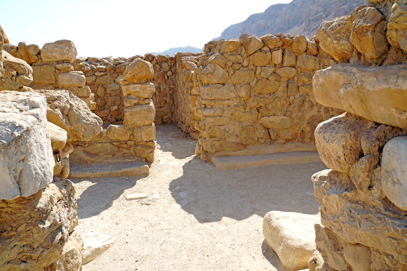 El yacimiento de Qumrán, junto a la orilla noroeste del mar Muerto, con las ruinas del asentamiento y, al fondo, los acantilados donde se abren las cuevas en las que aparecieron los Rollos del Mar Muerto (1947-1956). La identificación de esta comunidad con los esenios descritos por Josefo y Filón es la hipótesis mayoritaria, no un dato cerrado.